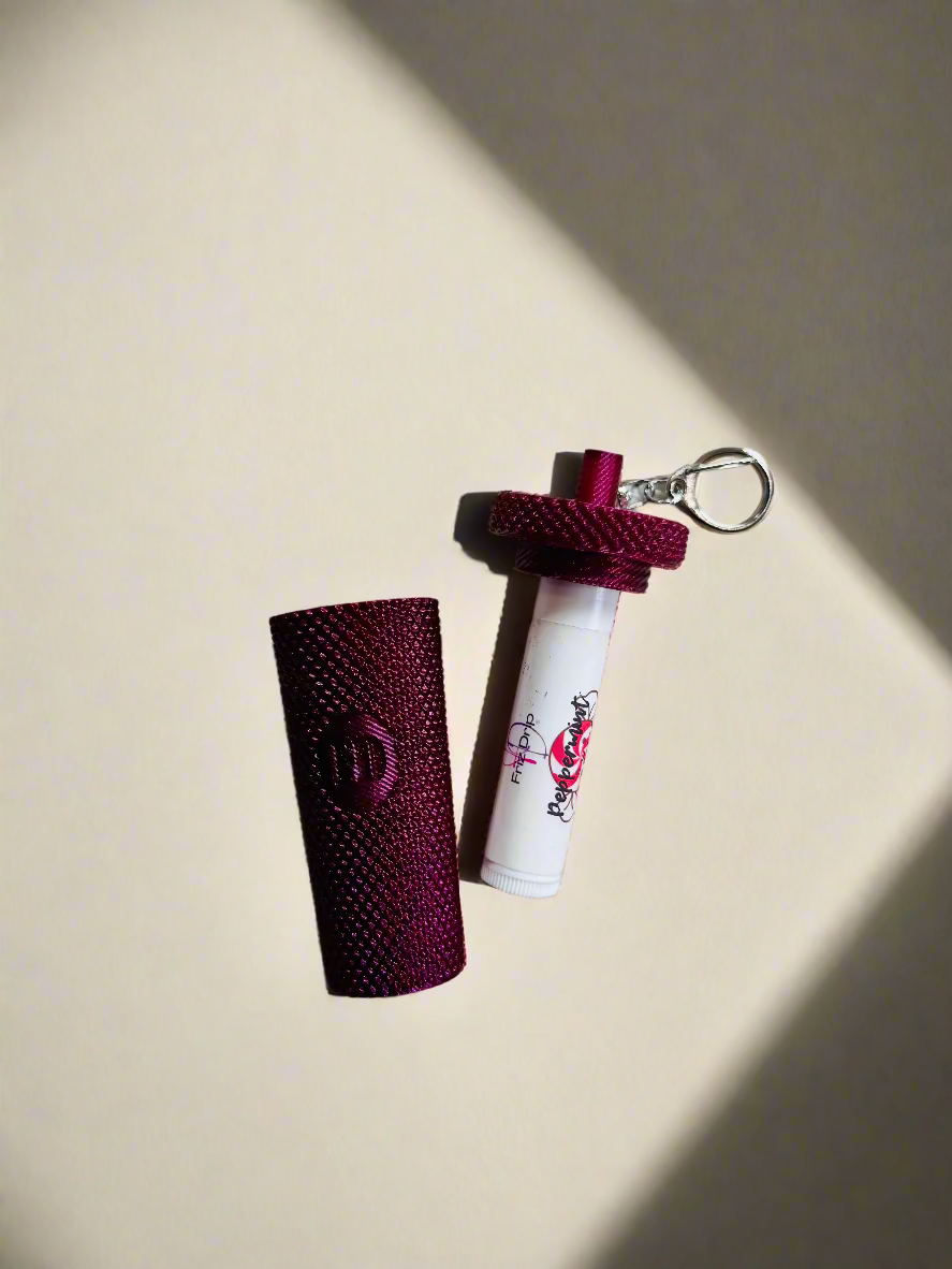 Maroon textured case and white cylindrical item with red design on a beige carpet